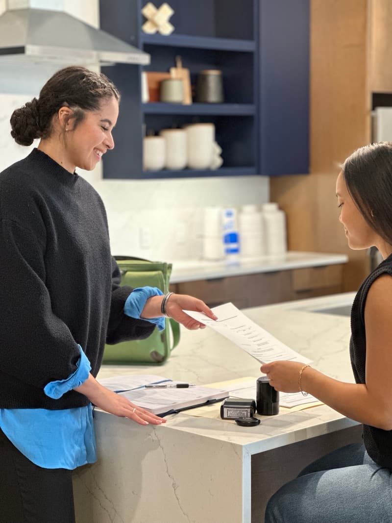 Ingrid Santos notarizing a document with a client at their Austin home